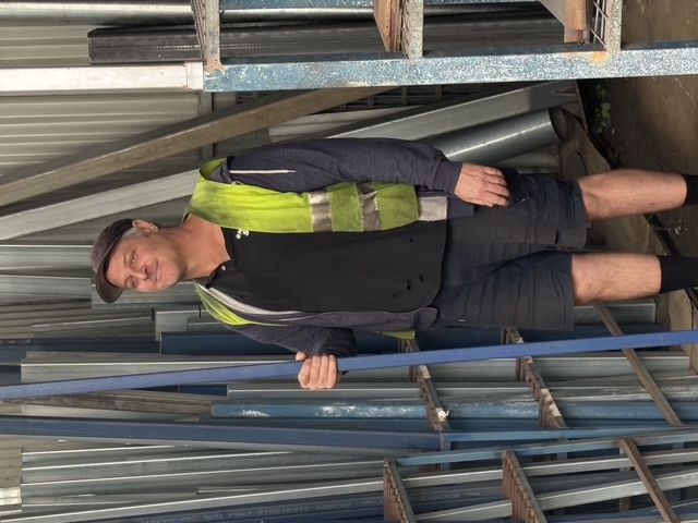 Marshall Steel yard hand in hi-vis, standing between the vertical stock racks