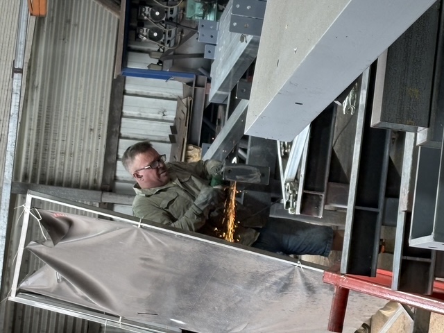 Fabricator grinding a bracket in the Marshall Steel workshop