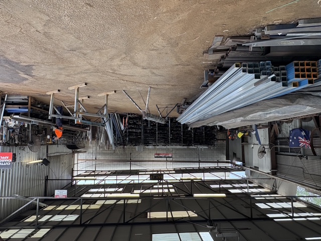 Wide view inside the Marshall Steel workshop — stock racks, benches and workers